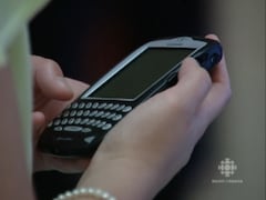 Téléphone BlackBerry avec clavier physique dans une main.