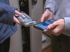 Deux étudiants tiennent leur téléphone cellulaire. 