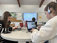 Des élèves pianotent sur les claviers d'ordinateurs portables dans une salle de classe. 