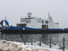 Un bateau flotte sur l'eau derrière une clôture. De la neige sale est amassée au pied de la clôture.