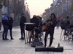 Un musicien s'exécute près de clients attablés en pleine rue.