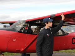 William Rousseau inspecte l'aile d'un petit avion rouge. 