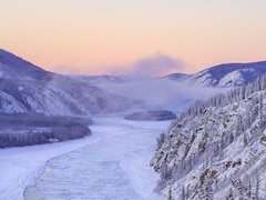 Un fleuve partiellement gelé entouré de montagnes, au Yukon