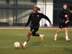 Un joueur de soccer, habillé tout en noir, s'apprête à frapper le ballon pendant un entraînement. 