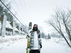 Émile Bergeron pose avec ses skis près d'un muret enneigé. 