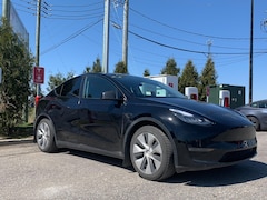 Une voiture électrique stationnée devant une borne de recharge Tesla.