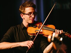 Un jeune homme joue du violon.