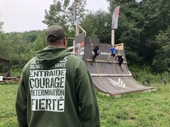 Des jeunes montent un mur d'escalade sous le regard de Serge Picard, responsable du camp. 