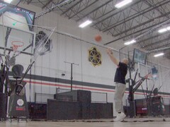 Un homme lance un balon de basketball dans un filet spécial surmonté d'un écran. Mai 2024.