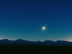 Une éclipse solaire au dessus d'une chaîne de montagnes.