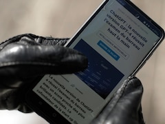 Une main qui tient un cellulaire avec un article sur le ChatGPT.