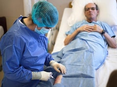 Une infirmière traite un patient allongé sur un lit d'hôpital.