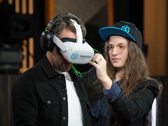 Une femme installe un casque de réalité virtuelle à un homme.