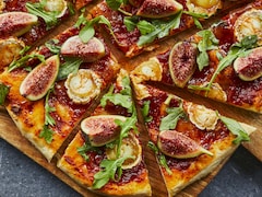 Une pizza aux figues et au fromage de chèvre sur une planche. 