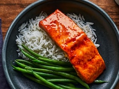 Une tranche de saumon glacé à l'érable est déposé sur du riz blanc, accompagné de haricots verts. 