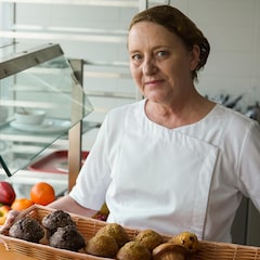 Une femme qui tient dans ses mains un panier rempli de muffins.