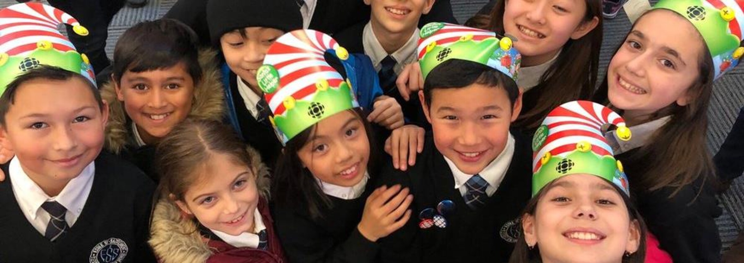 Des enfants portent des bonnets de lutin en carton avec le logo de Radio-Canada.