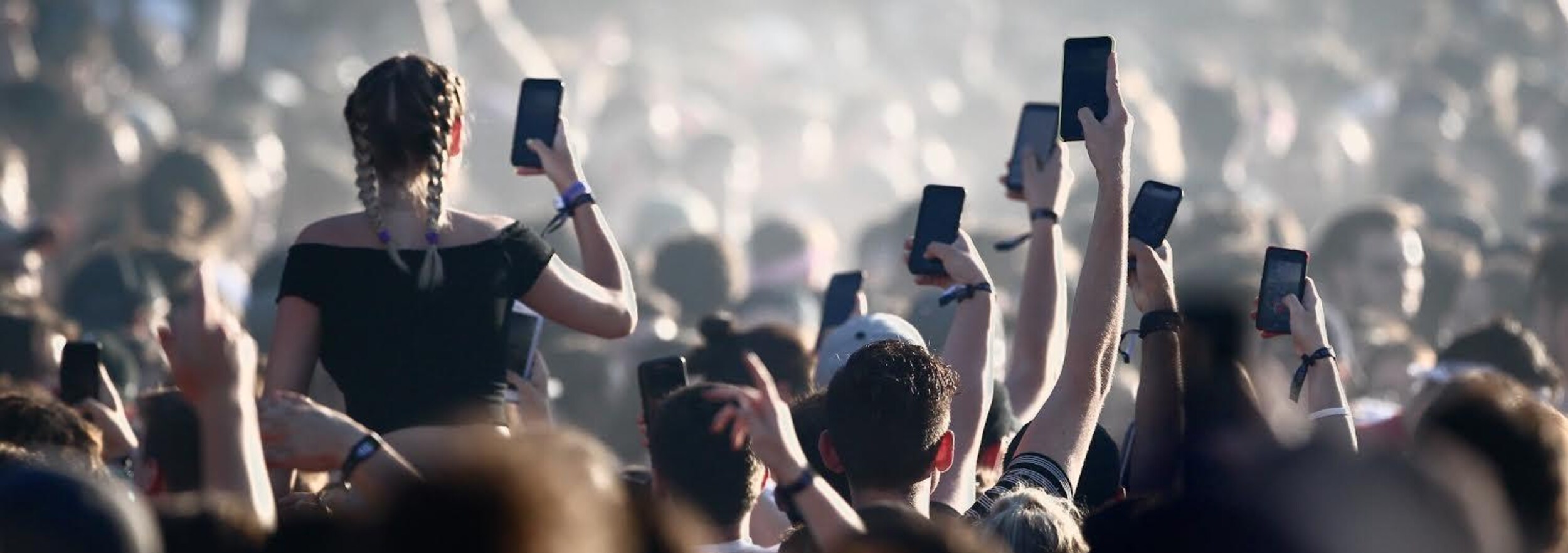 De nombreux spectateurs tiennent leur cellulaire dans leur main durant un concert.
