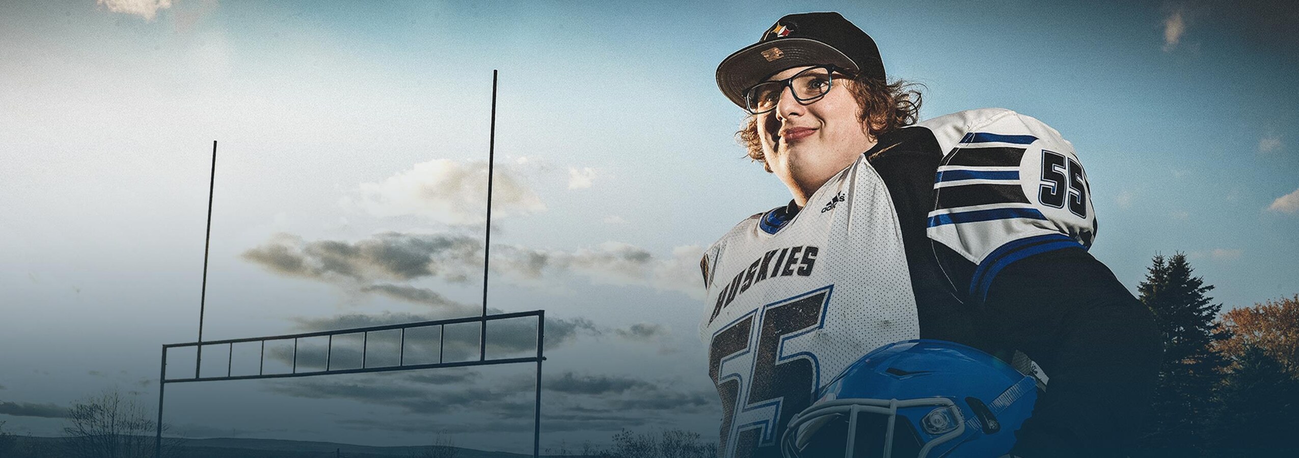 Autisme et football - La nouvelle famille de Raphaël Raphaël Guillemette tient son casque et regarde au loin en souriant.
