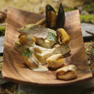 Des moules, un flanc carré au champignon sur une assiette en bois.