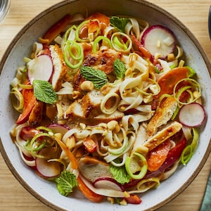 Un bol contenant la salade thaïe au poulet grillé et au poireau sur une table. 