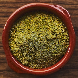Le sel aromatisé dans un petit plat de terre cuite sur un comptoir de bois. 