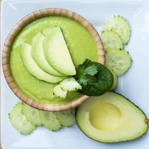 Un bol de soupe verte avec avocats et concombres.