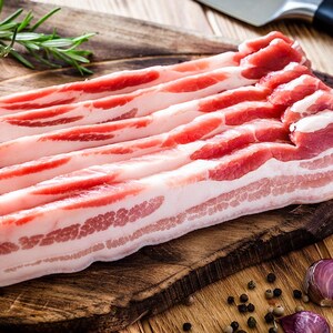 Plusieurs tranches de bacon sur une planche à découper.