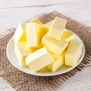 Un bol rempli de carrés de beurre sur une table en bois.