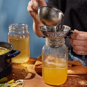 Deux pots en verre remplis de bouillon de poulet.