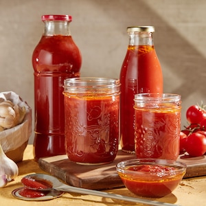 Cinq contenants en verre remplis de sauce tomate.