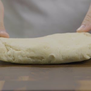 Un bloc de pâte est posé sur une planche à découper. 