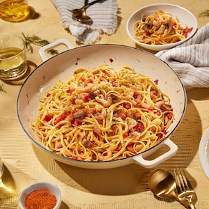 Un grand plat de linguines aux fruits de mer et deux bols prêts à être dégustés.