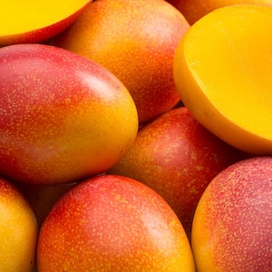Des mangues oranges entières et des mangues tranchées en deux.