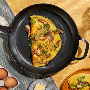 Une omelette recouverte de champignons et de verdure dans une poêle.