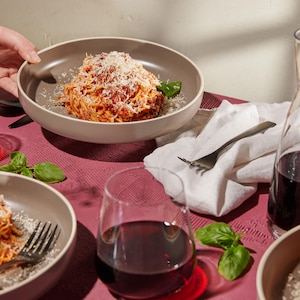 Trois assiettes de spaghetti servies avec du vin rouge.
