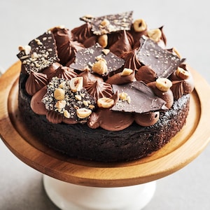 Un petit gâteau au chocolat sur un présentoir à gâteau.