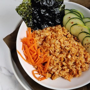 Un bol avec des légumes frais, des algues noris et du riz au tofu magique.