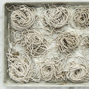 Nouilles soba crues divisées sur une plaque à cuisson.