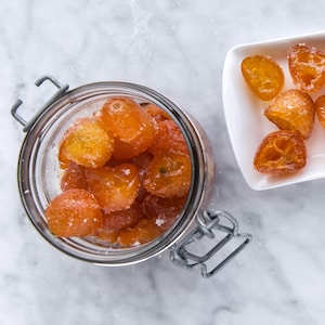 Kumquats confits au gingembre dans un pot. Kumquats frais dans un bol.