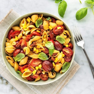 Un bol de coquilles au chorizo, aux tomates cerises et au maïs.