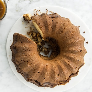 Un gâteau en forme de de Bundt et sauce caramel à côté.