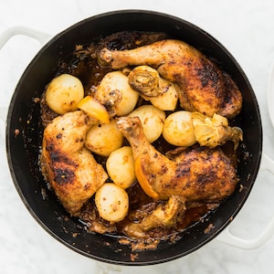 Une casserole remplie de cuisses de poulet, d'olives et d'artichauts et une assiette prête à être servie.