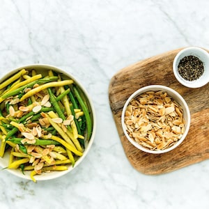 Un bol rempli d'haricots verts et jaunes garnis d'amandes.