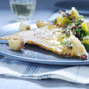 Une aile de raie saisie dans une assiette avec de l'ail confit.