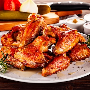 Plusieurs ailes de poulet dans une assiette.