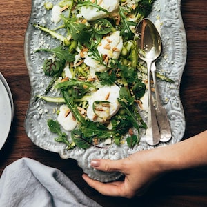 Une assiette de service avec une salade d'asperges aux amandes grillées avec des œufs pochés.