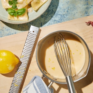 Une casserole de beurre blanc au citron près d'un plat de raviolis.