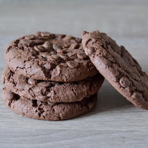 Quatre biscuits double chocolat sur une table.