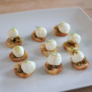 Neuf bouchées de chèvre et de fenouil dans une assiette.